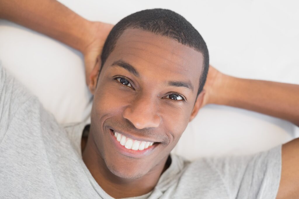 Close-up of smiling young man lying in bed
