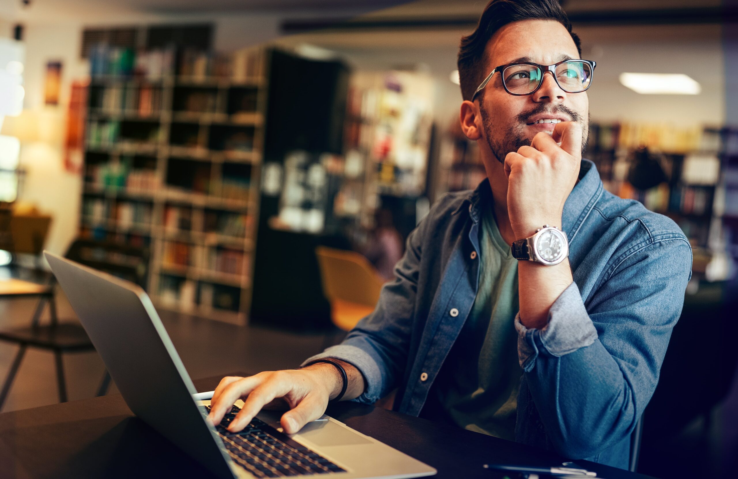 Young man studying in library, looking thoughtful