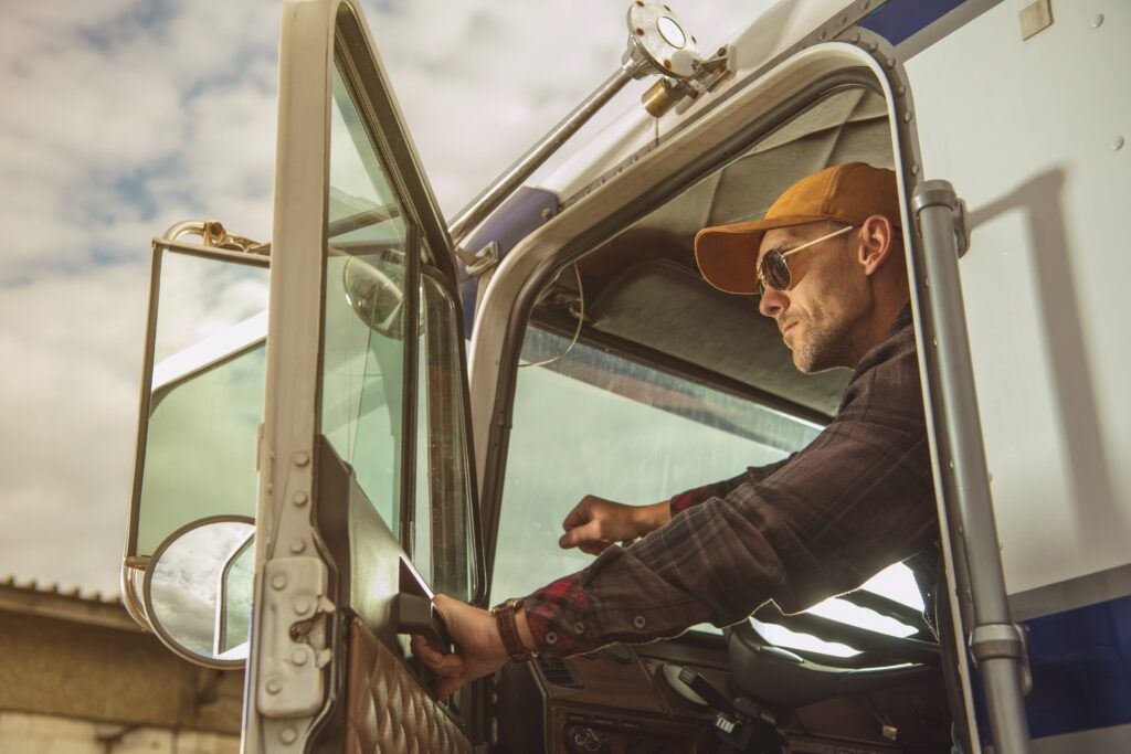 Truck driver sitting behind wheel, holding open door