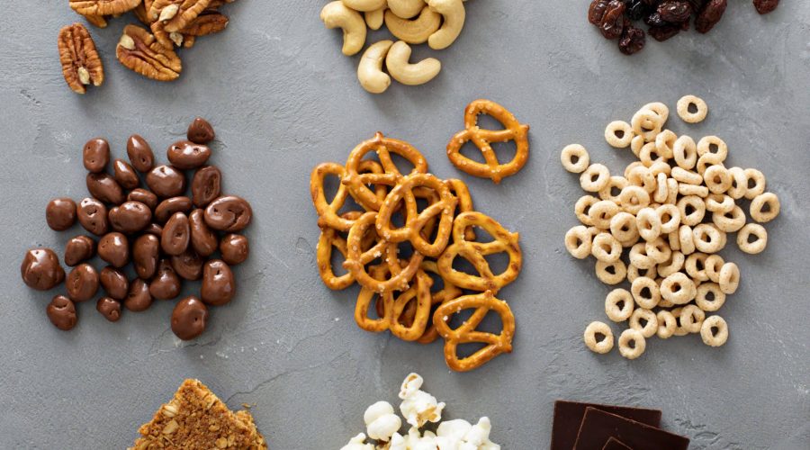 Small piles of healthy snacks like nuts, raisins, pretzels, popcorn, dark chocolate