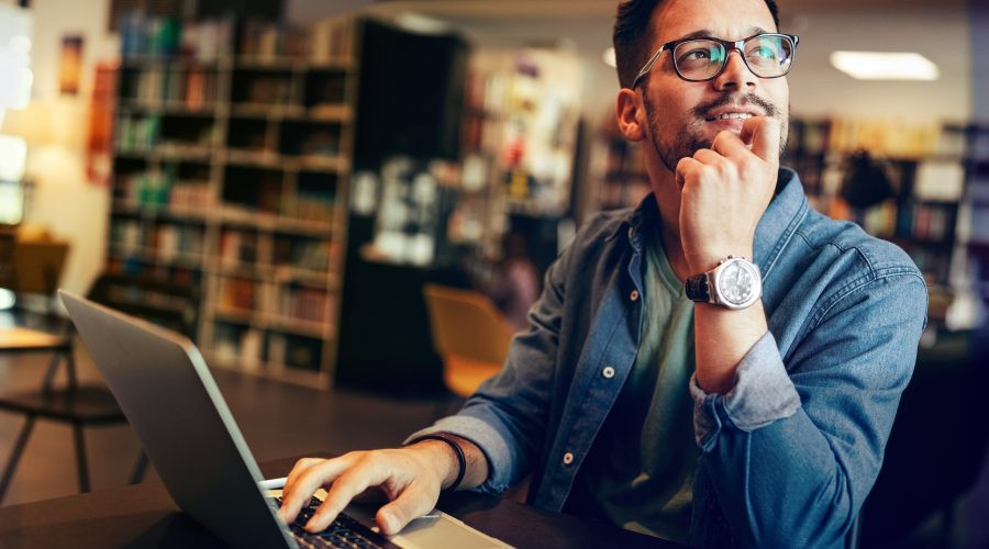 Young man studying in library, looking thoughtful